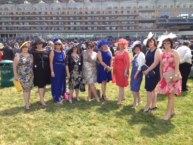 Group of friends in colourful dresses and hats, enjoying a day at the races