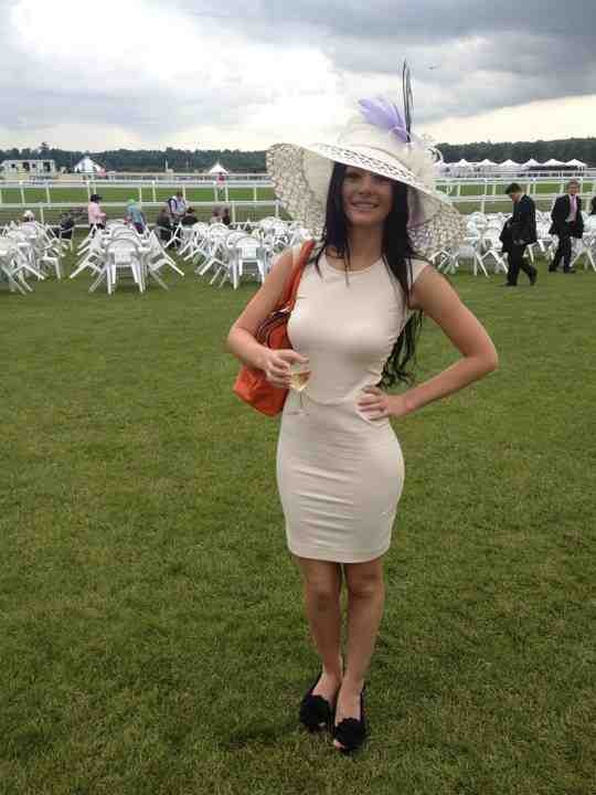 Client wearing a blush-pink dress with a cream wide-brimmed hat and lilac flower trim from the hire wardrobe