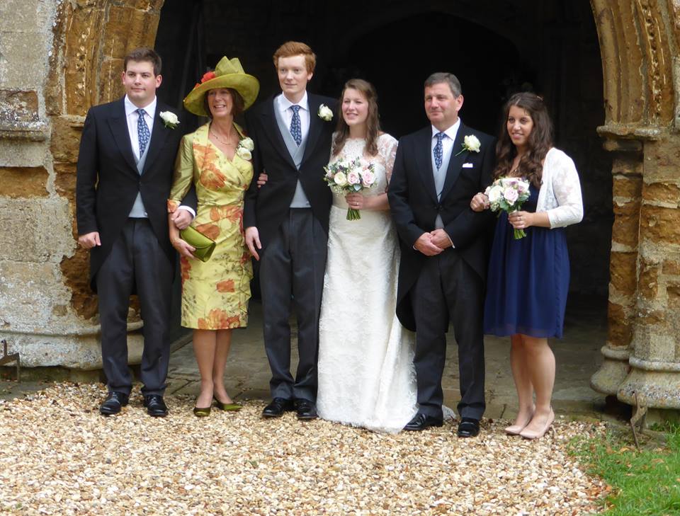 Wedding guests in soft green and ivory, with a coordinating wide-brimmed hat, at a country church