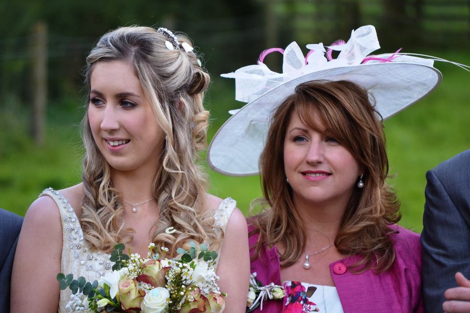 Bride and her mother, who is wearing a blush and ivory feathered fascinator