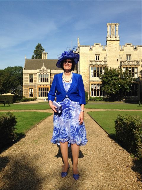 Guest in a cobalt blue dress and matching wide-brimmed hat in the gardens of a country house