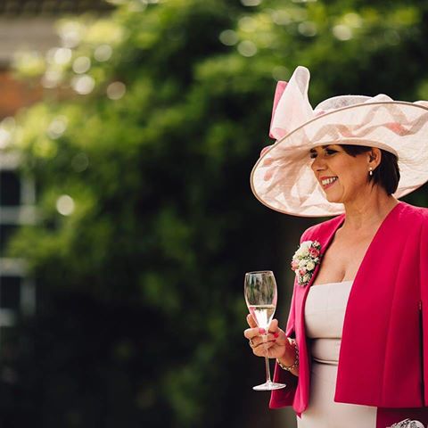 Guest in a wide-brimmed, feather-trimmed hat at a summer celebration