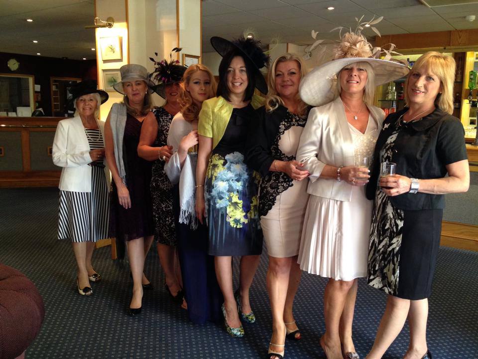A group of friends dressed for ladies’ day, in a line-up of fascinators and wide-brimmed hats