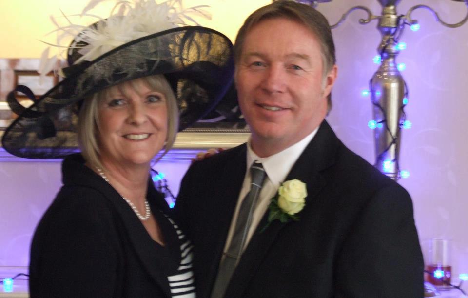 Guest at an evening wedding reception wearing a black wide-brimmed hat with cream feather trim
