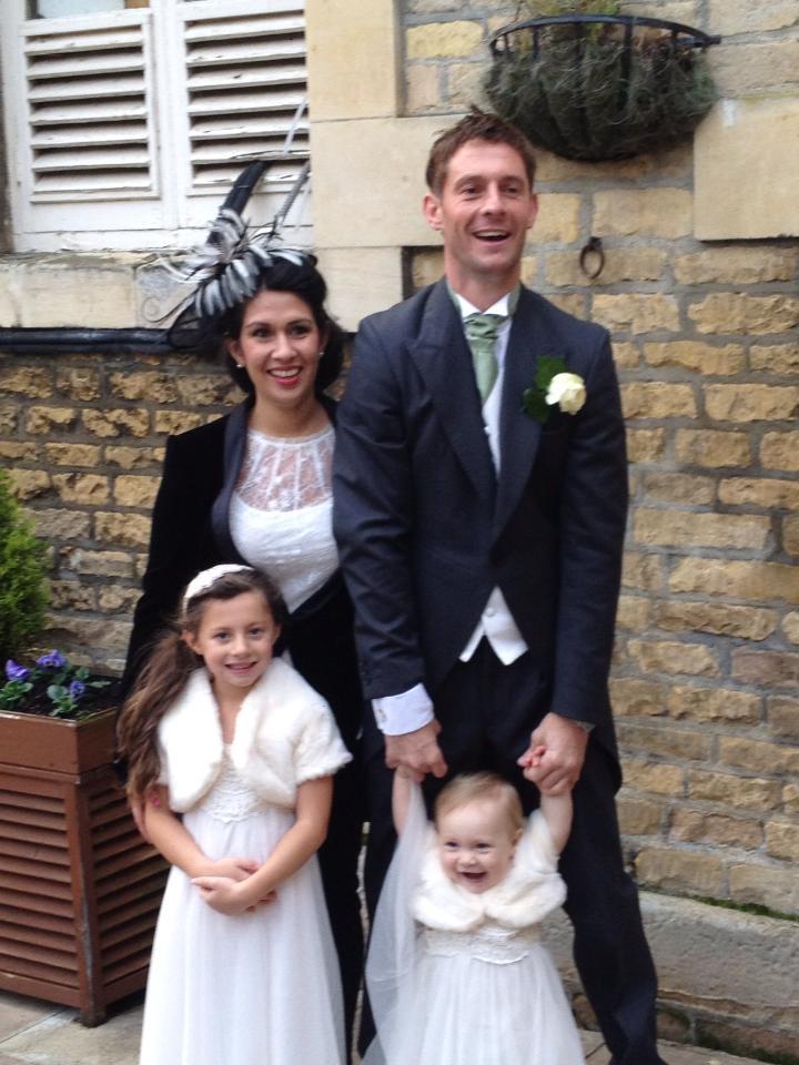 Guest wearing a black and white striped fascinator, with her husband and two daughters in white dresses